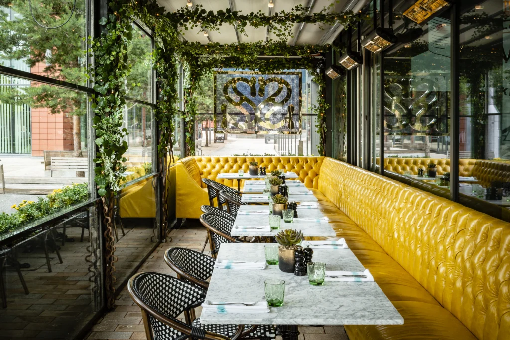 Artificial climbing Ivy above yellow coloured restaurant seats