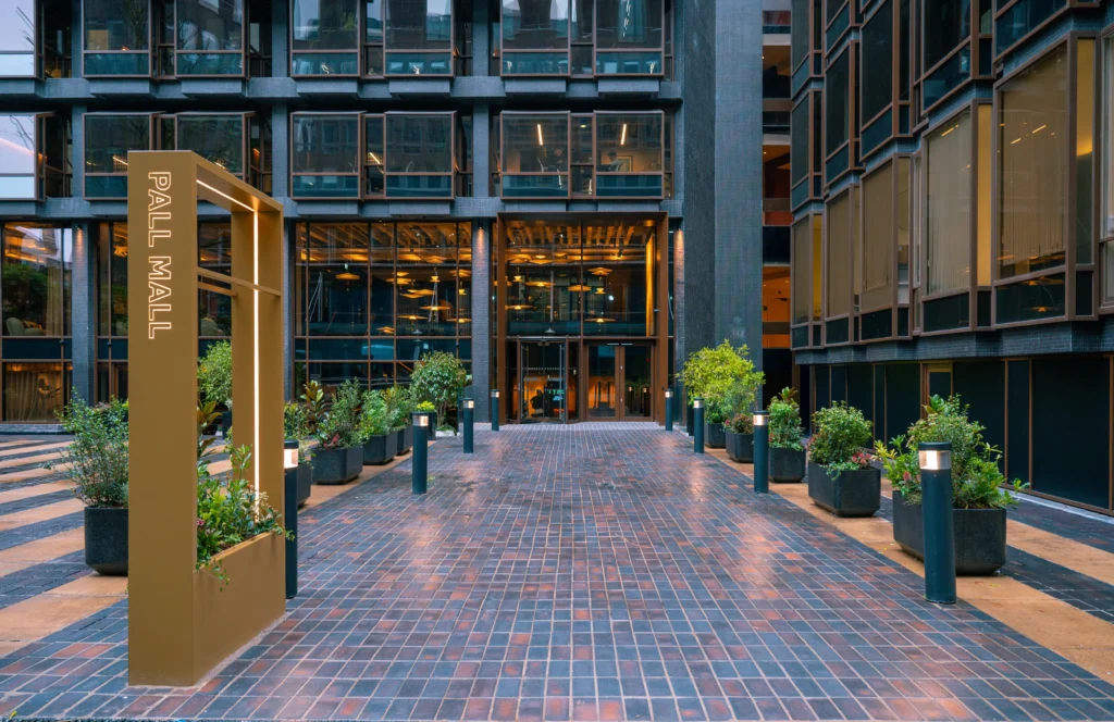 Pall Mall Plaza Manchester with gold coloured totem signage and live plants in troughs